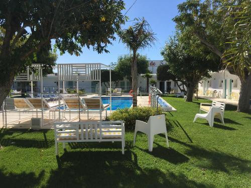 a group of chairs sitting in the grass near a pool at Hostal Las Cumbres in Conil de la Frontera