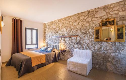 1 dormitorio con cama y pared de piedra en Can Salva, en Torroella de Fluvià