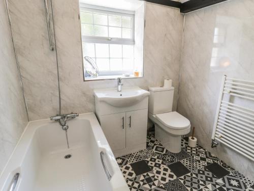 ein Badezimmer mit einer Badewanne, einem Waschbecken und einem WC in der Unterkunft The Stable Cottage in Llanbedr