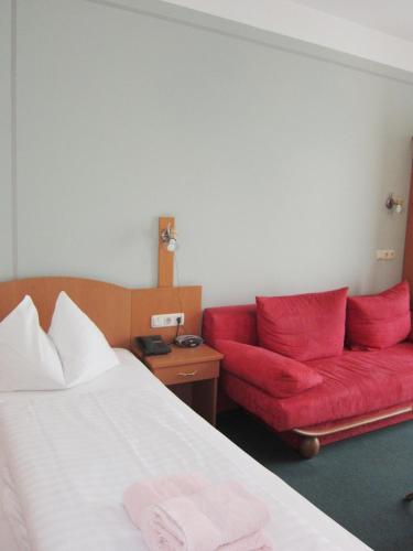 a hotel room with a bed and a red couch at Pension Elisabeth in Sankt Pölten