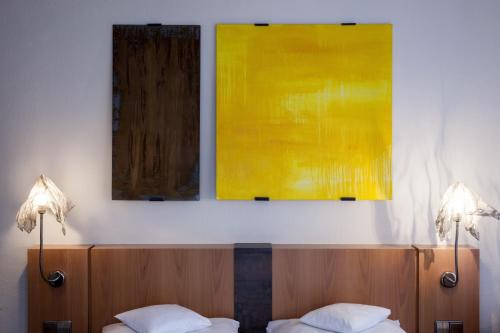 a bedroom with two paintings on the wall above a bed at Mintrops Stadt Hotel Margarethenhöhe in Essen