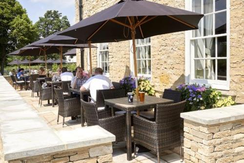 a group of people sitting at tables under an umbrella at The Evenlode Rooms at Firehouse Oxford in Witney