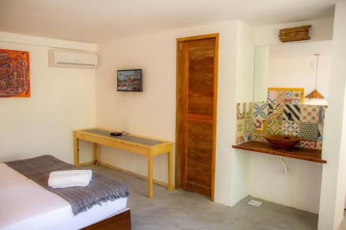 a room with a bed and a wooden table at Pousada Chez Toi in Jericoacoara
