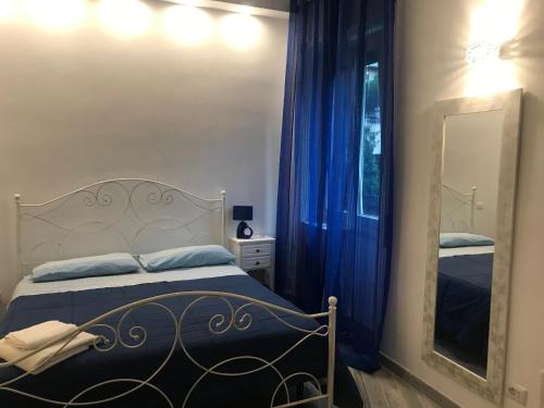 een slaapkamer met een bed met blauwe gordijnen en een spiegel bij LunaBlù Cinecitta' in Rome