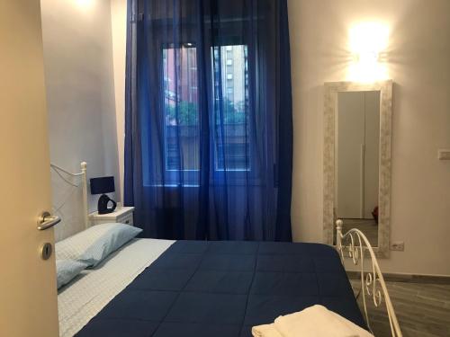 een slaapkamer met een bed en een raam met blauwe gordijnen bij LunaBlù Cinecitta' in Rome