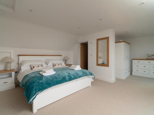 a white bedroom with a large bed and a mirror at Two Hoots in Kingsbridge