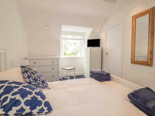 a bedroom with a bed and a dresser and a mirror at Summer Breezes in Newquay