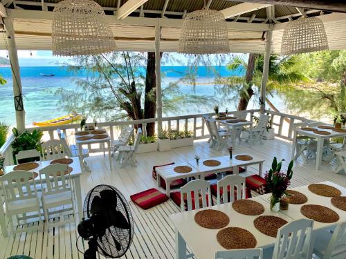 a restaurant with tables and chairs and a view of the ocean at Coconut Beach Bungalows in Chaloklum