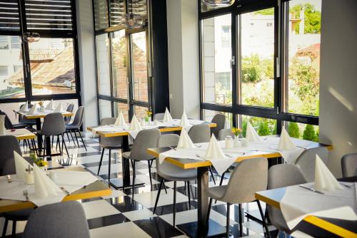restauracja ze stołami, krzesłami i oknami w obiekcie Villa Ljiljana w mieście Vinkovci