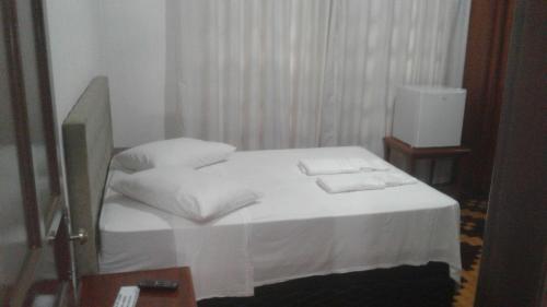 1 dormitorio con 1 cama con sábanas y almohadas blancas en Central 1, en Uruguaiana