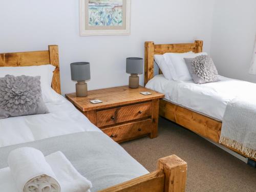 a bedroom with two beds and a table with two lamps at Highcroft in Belper