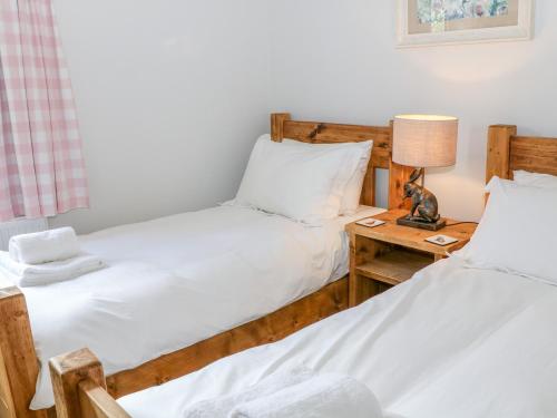 two twin beds in a room with a table with a lamp at Highcroft in Belper