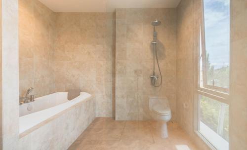 a bathroom with a tub and a toilet and a window at Sandbox Beachfront Villa 3 in Ban Krathing Lai