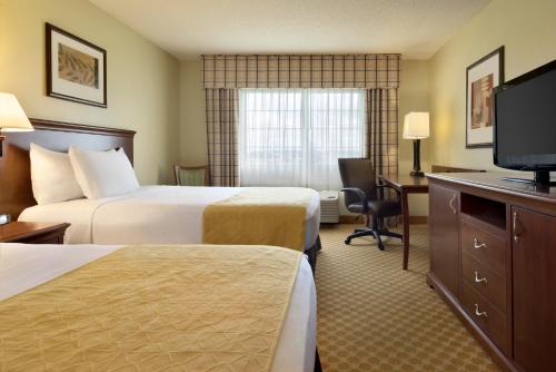 a hotel room with two beds and a flat screen tv at Country Inn & Suites by Radisson, Rochester, MN in Rochester