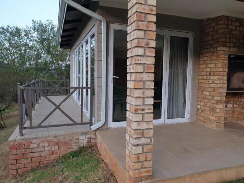 a house with a porch with a door and a balcony at Emfuleni Place by the River in Champagne Valley