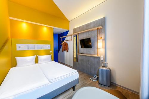 um quarto de hotel com uma cama e uma mala em ibis budget Strasbourg La Vigie em Ostwald