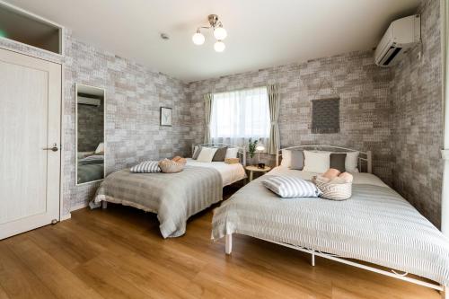 una camera con due letti e un muro di mattoni di ペンション マカナレアリゾート沖縄 a Ginowan