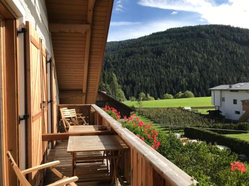 a balcony of a house with chairs and flowers at Platzerhof in Monguelfo