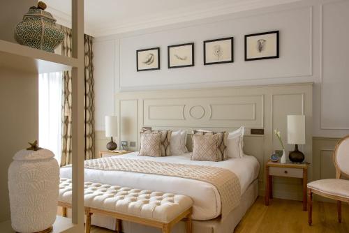a bedroom with a large white bed with a bench at Hôtel Chais Monnet & Spa in Cognac