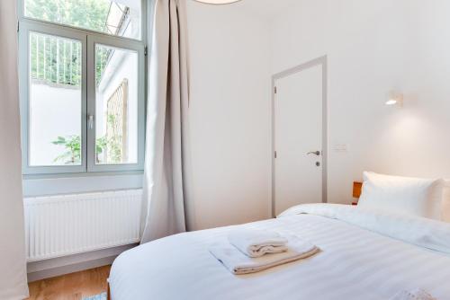 a white bedroom with two beds and a window at Newton Boutique Hotel Residences - Brussels EU Area in Brussels