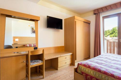 a bedroom with a desk and a bed and a mirror at Hotel Stella Alpina in Andalo