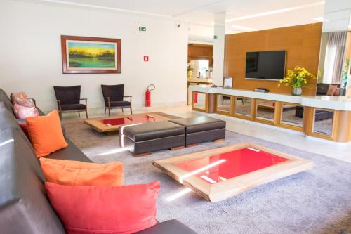 sala de estar con sofá y TV en Hotel Vale Verde, en Campo Grande