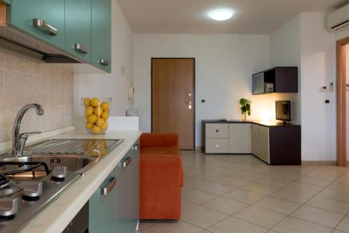 a kitchen with a sink and a living room at Hotel Baltic in Giulianova
