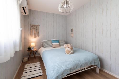 a small bedroom with a bed with a blue blanket at ペンション マカナレアリゾート沖縄 in Ginowan