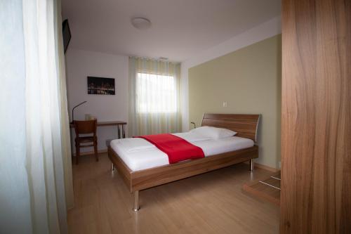 a bedroom with a bed with a red blanket on it at Motel Mühle in Wollerau