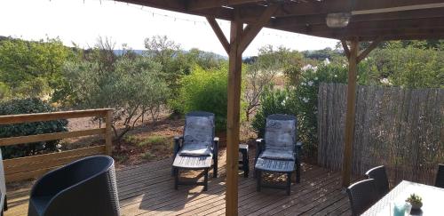 two chairs and a table on a wooden deck at Lous Roussels in Le Bosc