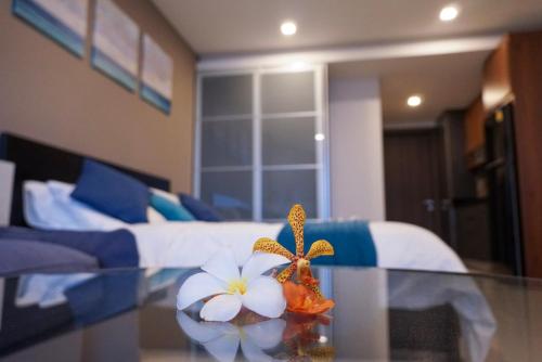 a room with a bed and a glass table with flowers at Beachfront Executive Studio Mae Phim in Rayong