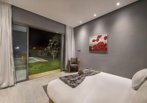 a bedroom with a bed and a large window at Palms Edge Villas avec Piscine & Jardin Privés in Marrakech