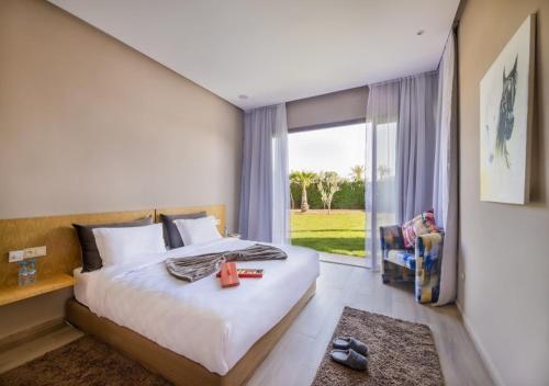 ein Schlafzimmer mit einem Bett und einem großen Fenster in der Unterkunft Palms Edge Villas avec Piscine & Jardin Privés in Marrakesch