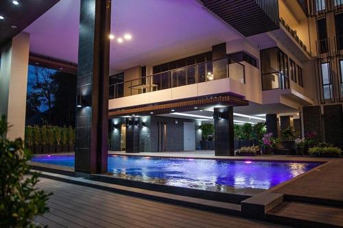 a house with a swimming pool in front of a building at Beachfront Executive Studio Mae Phim in Rayong
