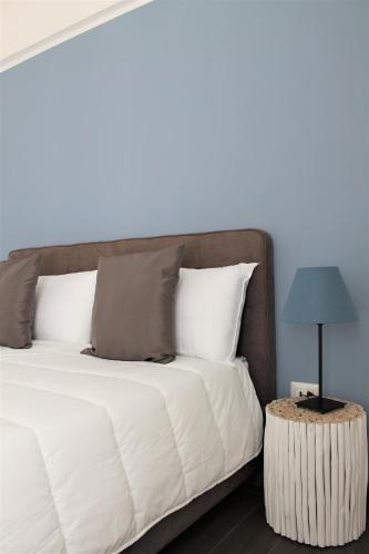 a bed with white sheets and a blue lamp on a table at Residence Pola in Catania