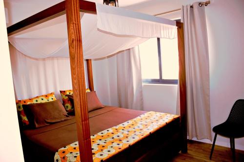 a bedroom with a four poster bed with a window at Kasa Imbondeiro in Mindelo