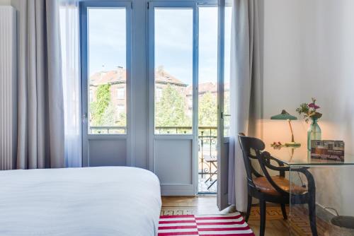 a bedroom with a bed and a desk and a window at Newton Boutique Hotel Residences - Brussels EU Area in Brussels