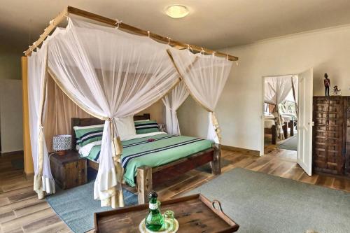 a bedroom with a canopy bed and a table at Olerai Lodge in Arusha