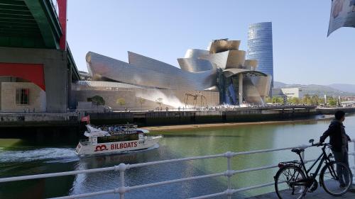 a boat in a river with a building and a bike at Apartamento céntrico con vistas a la Ría! garaje, ideal 2-4 in Bilbao