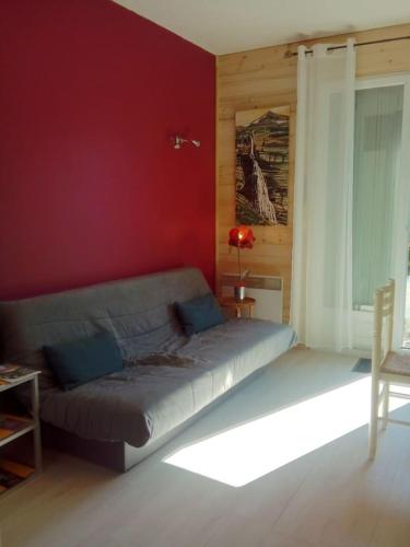 a living room with a bed in a red wall at Camp de base in Le Bourg-dʼOisans