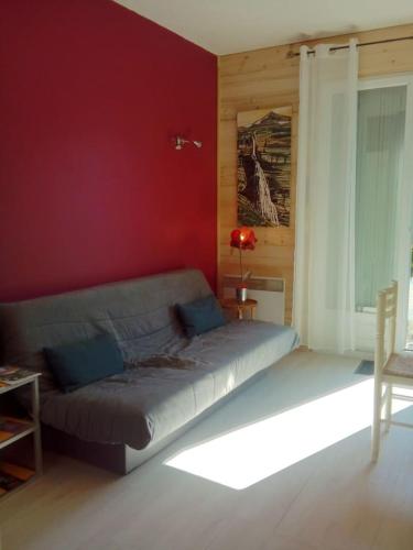 - un salon avec un lit dans un mur rouge dans l'établissement Camp de base, au Bourg-dʼOisans