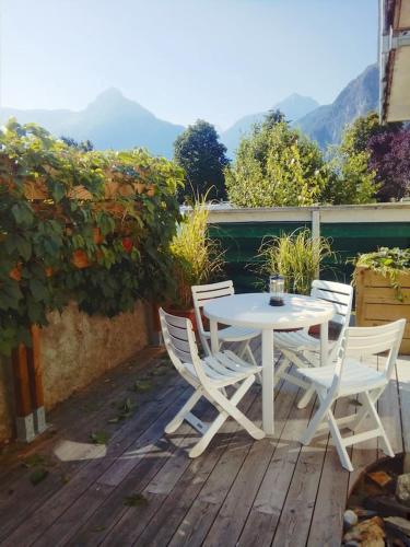 une table et des chaises blanches sur une terrasse en bois dans l'établissement Camp de base, au Bourg-dʼOisans