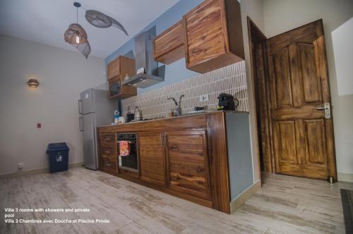 a kitchen with wooden cabinets and a sink and a door at Villa centre Grand Baie in Grand Baie