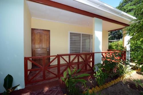a balcony of a house with a wooden railing at Le Relax Self Catering Apartment in La Digue