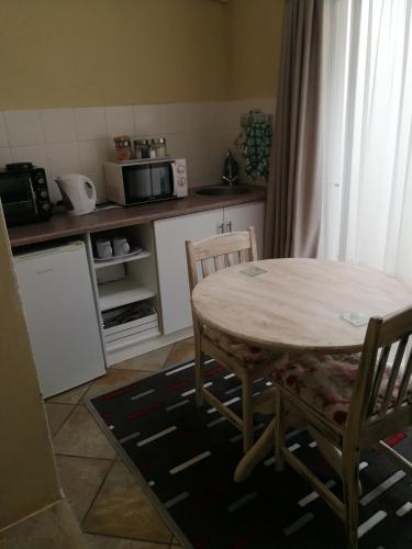 a kitchen with a table and two chairs and a table and a counter at Big Tree Guesthouse Brits in Brits