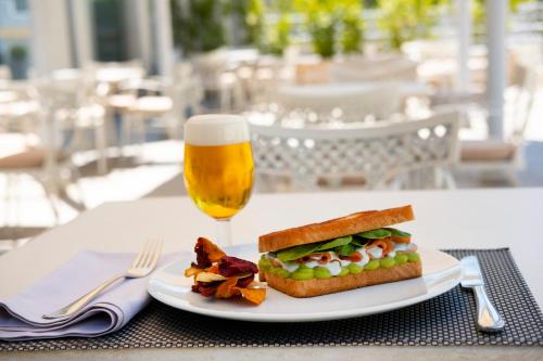 a sandwich on a plate next to a glass of beer at Hotel Attica21 Las Rozas in Las Rozas de Madrid