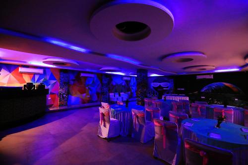 a room with purple lights and white tables and chairs at V One Pride in Jaipur