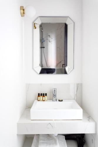 une salle de bain avec un lavabo blanc et un miroir dans l'établissement Habitat Parisien - Ponthieu Champs Elysées, à Paris