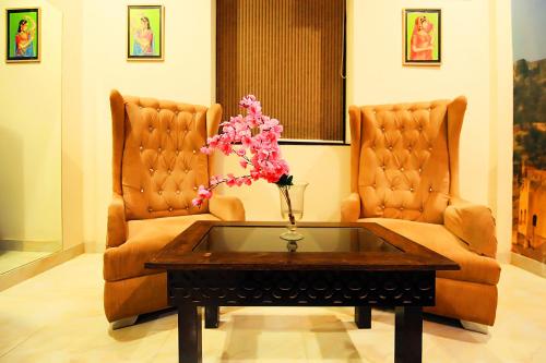 a living room with two chairs and a table with flowers at V One Pride in Jaipur