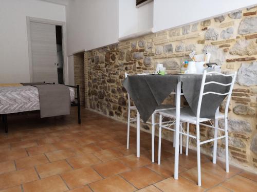 una mesa y sillas en una habitación con una pared de piedra en B&B Aika 48, en Troia